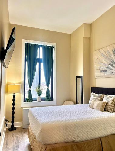 a bedroom with a bed and a window with blue curtains at The Nest At Twelve in Detroit