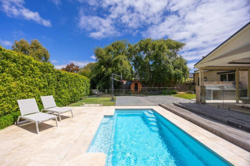 a swimming pool with two chairs next to a house at Play on Balcombe in Mount Martha