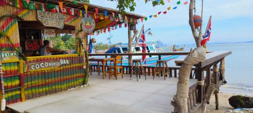 a restaurant on the beach with tables and chairs at Kohmook cocobeach in Koh Mook
