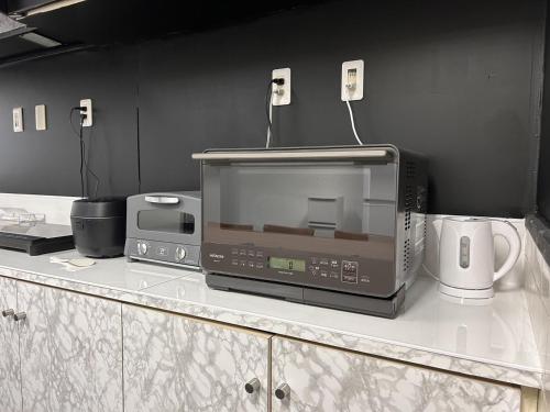 宫古岛女性専用 dormitory all good的厨房台面上的一个微波炉