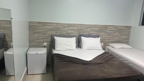 a bedroom with a bed and a brick wall at POUSADA DA MAGA in Chapada dos Guimarães