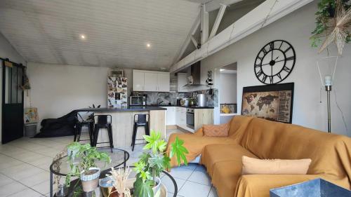 a living room with a couch and a clock on the wall at Charmante maison t3 avec 2 chambres et jardin clos in Carquefou
