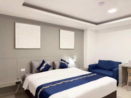 a bedroom with a large bed and a blue chair at UTD8 Hotel and Residence in Bangkok