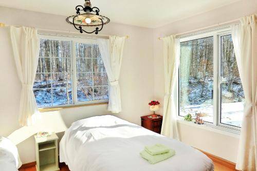 een slaapkamer met een bed en twee ramen bij 丘の上白亜の洋館風別荘静かな小さなお宿Guest House Itoh 2名様から6名様 in Asahikawa