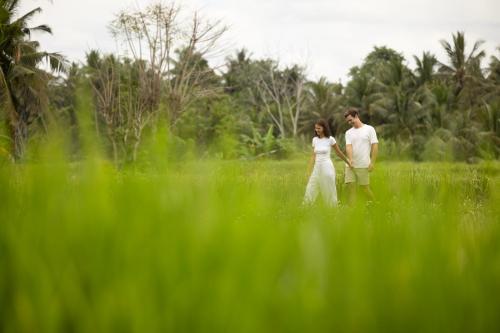 Un uomo e una donna in piedi in un campo di Beehouse Dijiwa Ubud ad Ubud