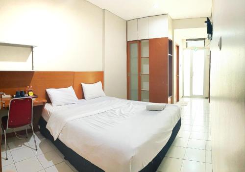 a bedroom with a large bed and a desk with a chair at Sang Surya Guest House in Bandung