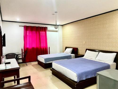 a hotel room with two beds and a red curtain at Shine Hotel in Sampong