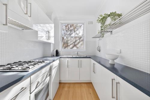 a white kitchen with a stove and a sink at Sunny Manly Escape 2 min walk to beach in Sydney