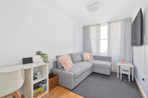 a living room with a couch and a tv at Sunny Manly Escape 2 min walk to beach in Sydney