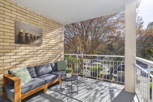 a balcony with a couch and a large window at Sunny Manly Escape 2 min walk to beach in Sydney