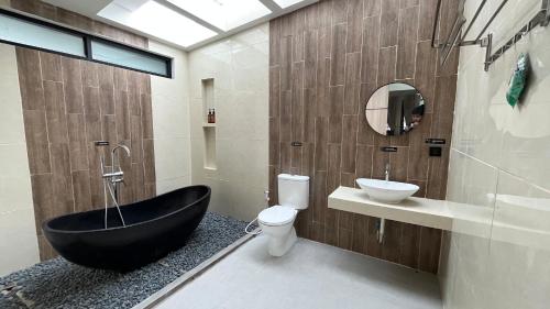 een badkamer met een zwart bad naast een toilet en een wastafel bij Patria Villa Kayen in Kejayan