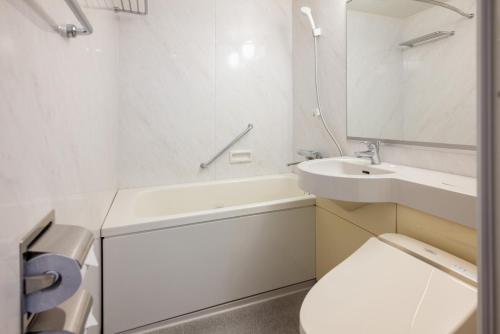a white bathroom with a toilet and a sink at Hotel Global View Urawa in Saitama