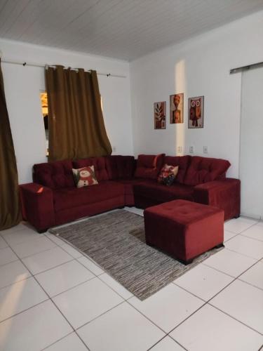een woonkamer met een rode bank en een rode poef bij Ambiente Família e acolhedor in Porto Seguro