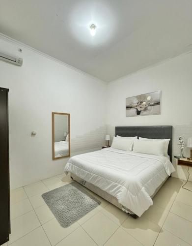 a white bedroom with a large bed and a mirror at Spacious House - Ngemplak, Surakarta in Kadipiro