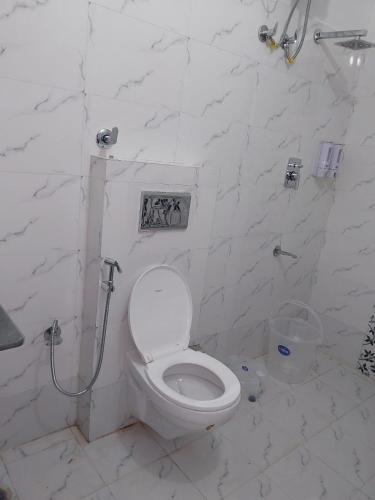 a white bathroom with a toilet and a shower at Hotel Dharam Ganga in Uttarkāshi