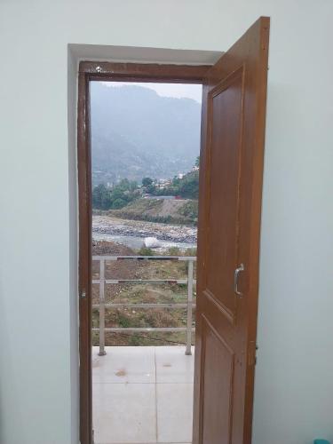 an open door to a balcony with a view at Hotel Dharam Ganga in Uttarkāshi