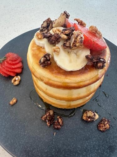 Ein Pfannkuchen mit Früchten und Nüssen auf einem blauen Teller in der Unterkunft Azure Suites, Tibubeneng, Canggu in Dalung