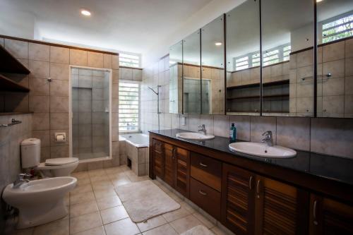un bagno con due lavandini e un WC di The Villa - Le Morne - Kite, Golf & Beach a Le Morne