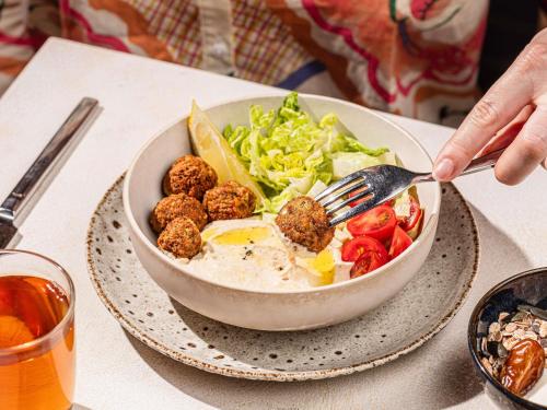 une personne mangeant un bol de salade avec fourchette dans l'établissement Novotel Jakarta Mangga Dua Square, à Jakarta