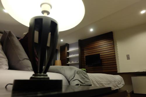 a bedroom with a bed and a table with a lamp at Villa Rassada Nakorn Lampang in Lampang