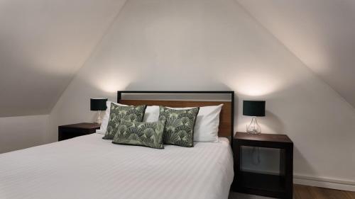 ein Schlafzimmer mit einem weißen Bett und zwei Nachttischen in der Unterkunft Flowerpot Cottage Hideaway in Middleton