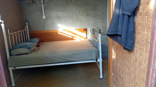 un piccolo letto in una stanza con una luce sopra di Rootscamp a Surinam