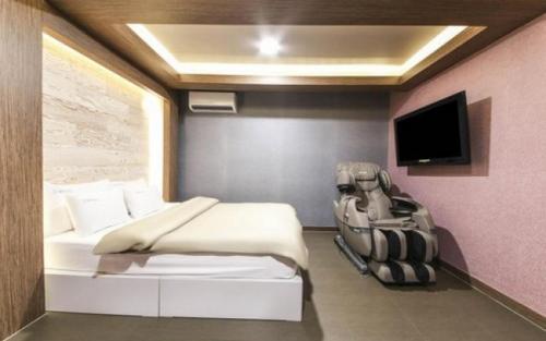 a bedroom with a bed and a tv on a wall at SU Motel in Gumi