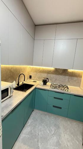 a kitchen with blue cabinets and a sink at Kurmangazy in Zhezdi