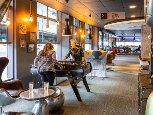 a couple playing a game of foosball in a restaurant at ibis Birmingham Airport Terminal Building - NEC in Bickenhill