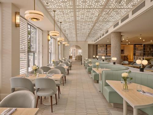 a dining room with tables and chairs and windows at InterContinental Sydney Coogee Beach by IHG in Sydney