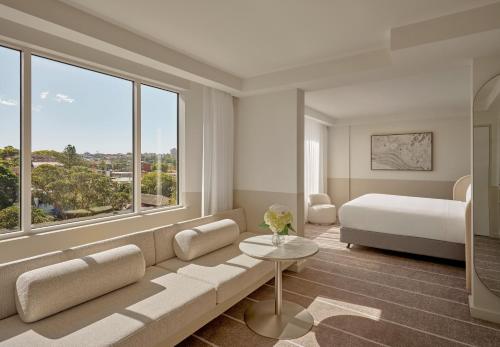 a living room with a couch and a bed and windows at InterContinental Sydney Coogee Beach by IHG in Sydney