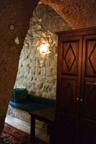 a room with a stone wall with a blue couch at Dreams Cave Hotel in Ortahisar