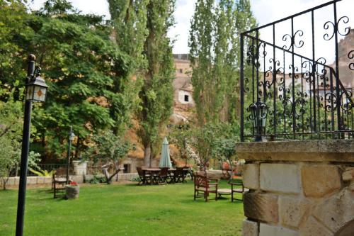a park with tables and chairs and a wrought iron fence at Dreams Cave Hotel in Ortahisar