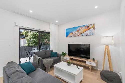 a living room with a couch and a tv at Saltwater Escape - Live the Sand and Surf Lifestyle in Wollongong