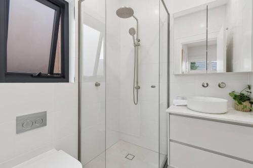 a white bathroom with a shower and a sink at Saltwater Escape - Live the Sand and Surf Lifestyle in Wollongong