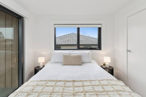 a white bedroom with a large bed and a window at Saltwater Escape - Live the Sand and Surf Lifestyle in Wollongong