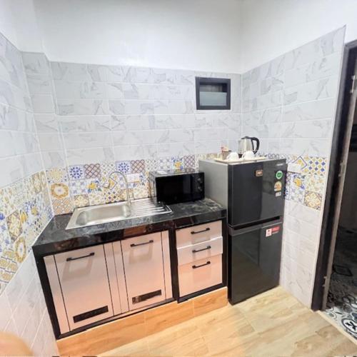 a small kitchen with a sink and a refrigerator at Stingless Villa in Ban Ket Ho