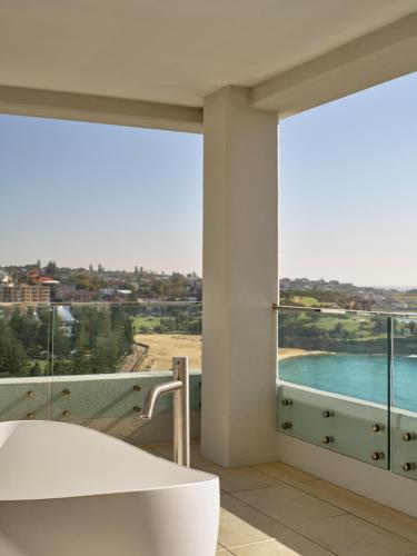 a bathroom with a tub and a view of the water at InterContinental Sydney Coogee Beach by IHG in Sydney