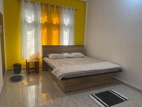 a bedroom with a bed with yellow walls and windows at Jorhat HideAway in Jorhat