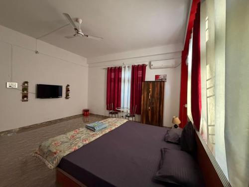 a bedroom with a bed with red curtains and a tv at Jorhat HideAway in Jorhat