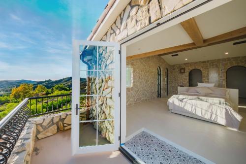 a bedroom with a balcony with a bed and a glass door at Mintcello Estate in Malibu