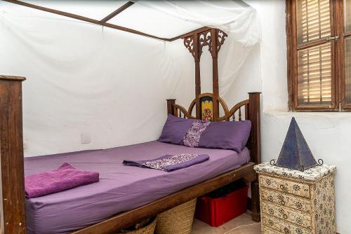 a bed in a room with purple pillows on it at Ella's Swahili House in Bagamoyo