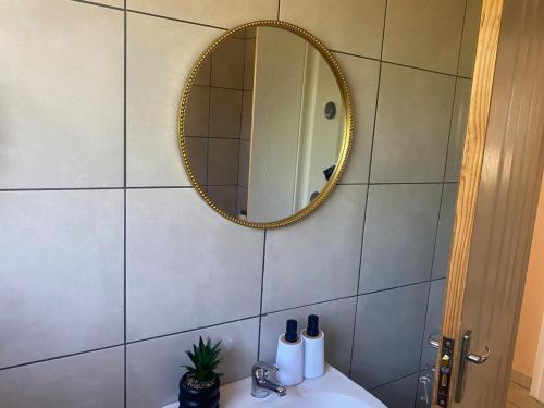 une salle de bain avec un lavabo et un miroir au mur dans l'établissement Cozy Haven in Manzini, à Manzini