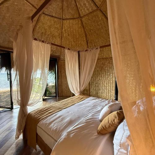 una camera da letto con letto a baldacchino con tende di Cambaya Beach Resort a Busuanga