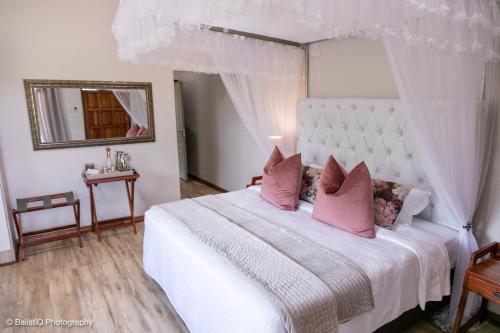 een slaapkamer met een groot wit bed met roze kussens bij The Sissing Santuary 