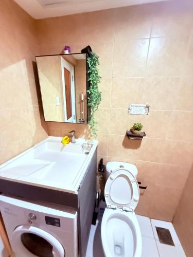 a bathroom with a toilet and a sink and a mirror at Fyangz Mini Karaoke Condo Staycation in Minglanilla