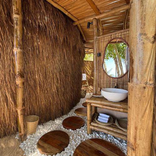 un bagno con un lavandino e uno specchio in una capanna di Cambaya Beach Resort a Busuanga