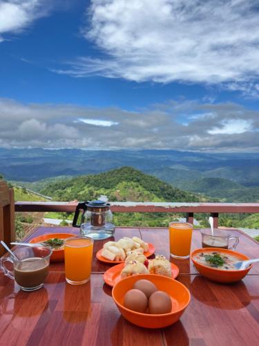 einem Holztisch mit Teller mit Lebensmitteln und Orangensaft in der Unterkunft บ้านกระจก - Raiwassana Baandoy in Ban Dong