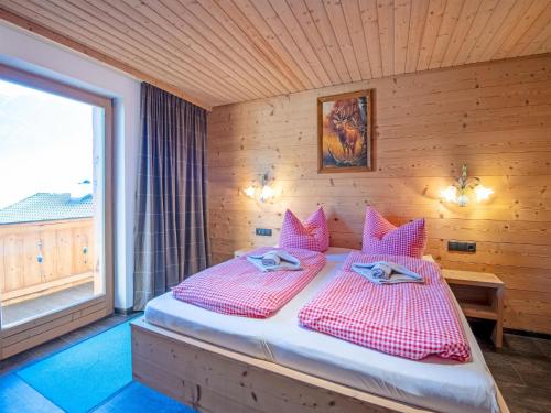 a bedroom with a bed with pink pillows and a window at Cabin with sauna near Spieljoch Ski in Pankrazberg