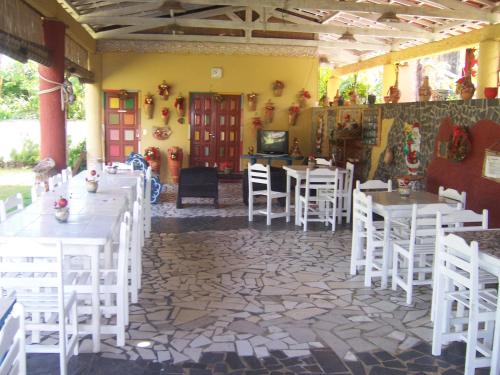 a dining room with white tables and white chairs at Albergue da Gamboa in Morro de São Paulo